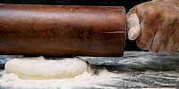 Mężczyzna wałkuje ciasto na stolnicy